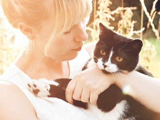 Eine Frau mit blonden Haaren hält im Freien eine schwarz-weiße Katze. Der Text lautet: „Tierhaarallergie: Erklärung, Therapie, Tipps für Sie“ und „Was, wann und wie bei Allergien“. Das Logo oben lautet „allergopharma“.